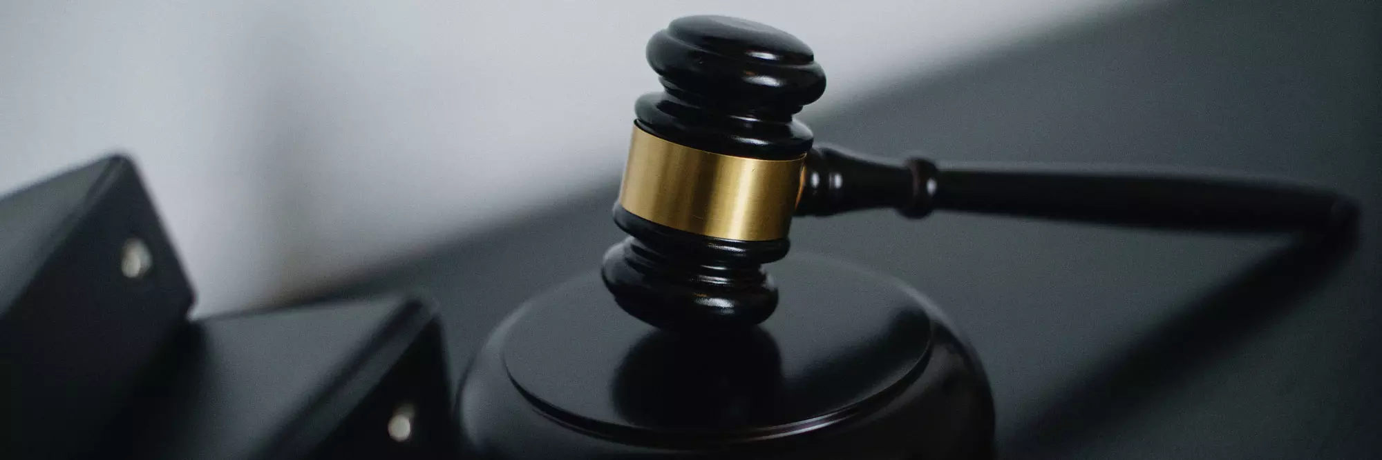 Consulenza Legale. Martello del giudice, simbolo della giustizia, posizionato su una superficie scura. Dettagli in oro rappresentano l'autorità legale.